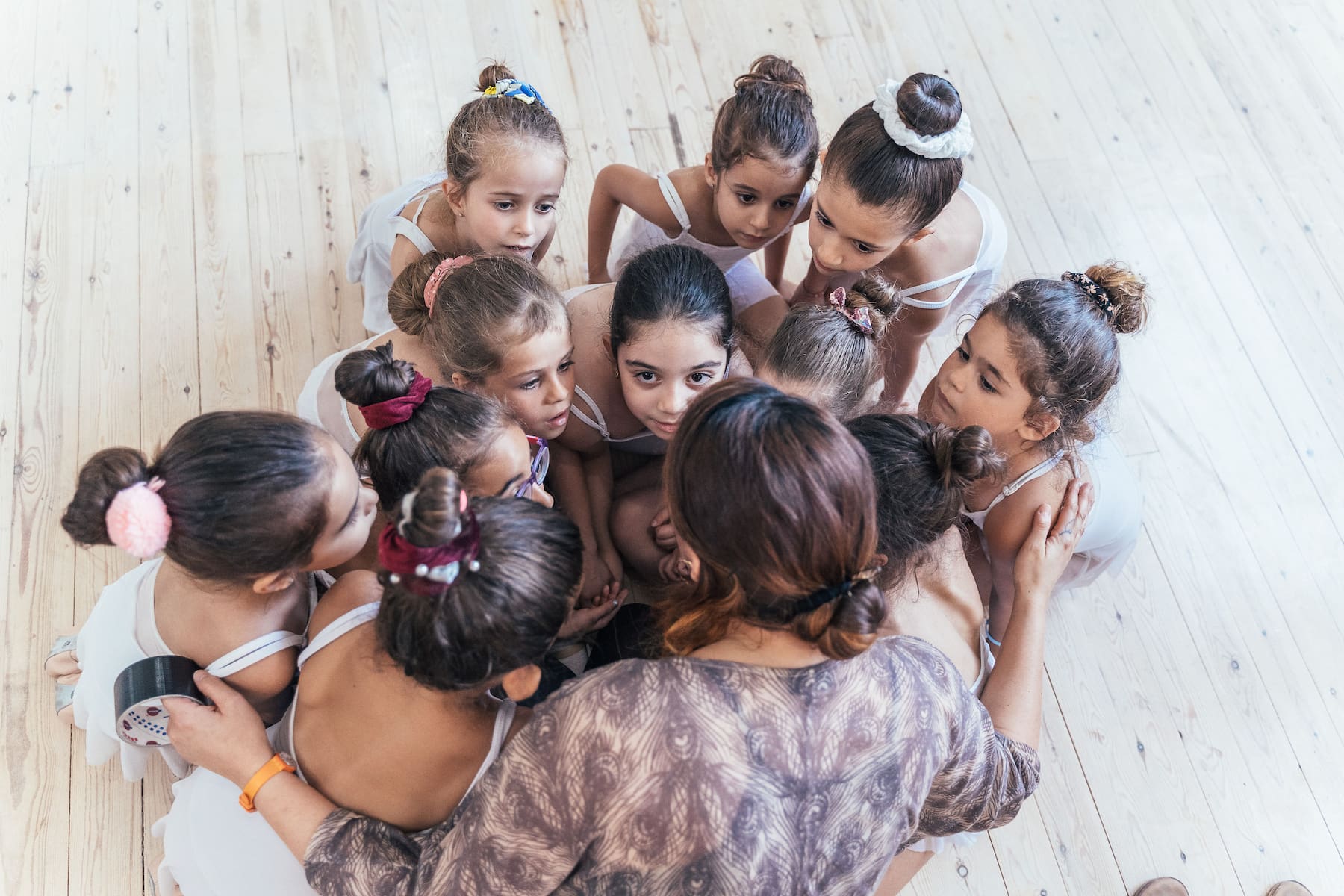 young ballerinas gathered around their teacher